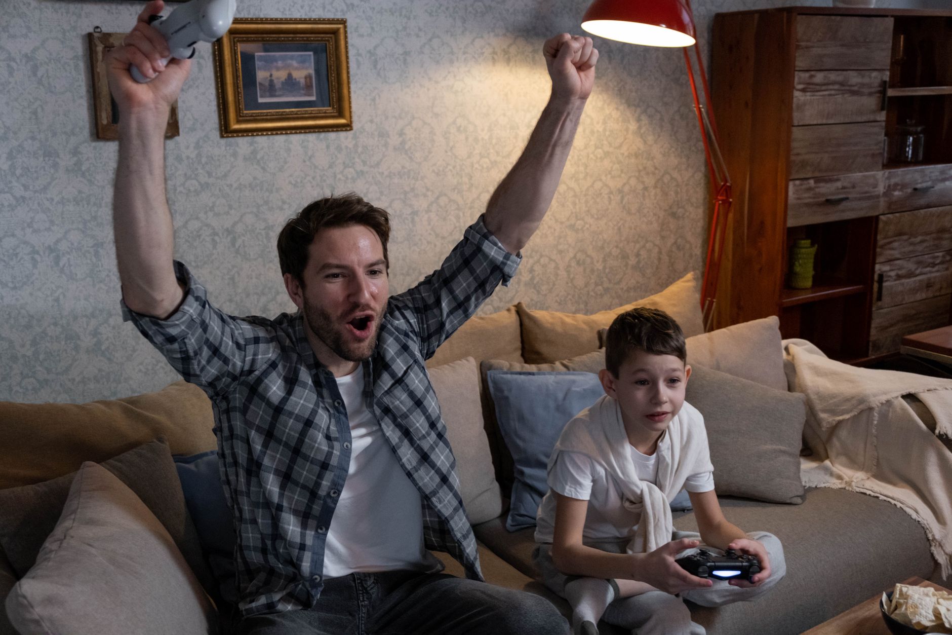 Two children playing a video game together on a couch with controllers in hand