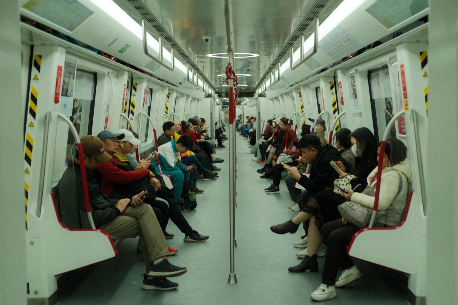 Person playing a handheld gaming device during a subway commute