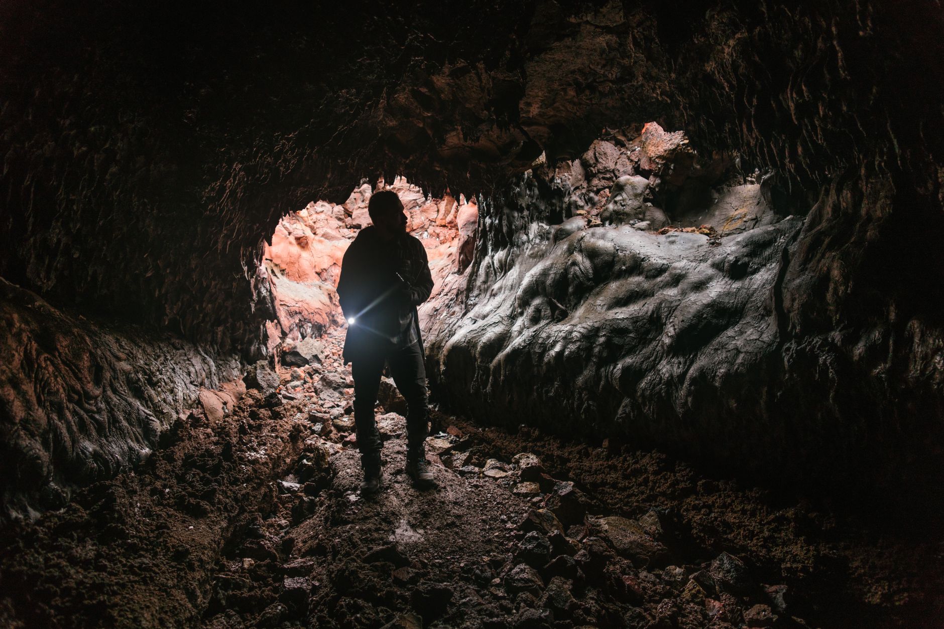 A dark underground cave environment with layered rock formations, representing vertical level design