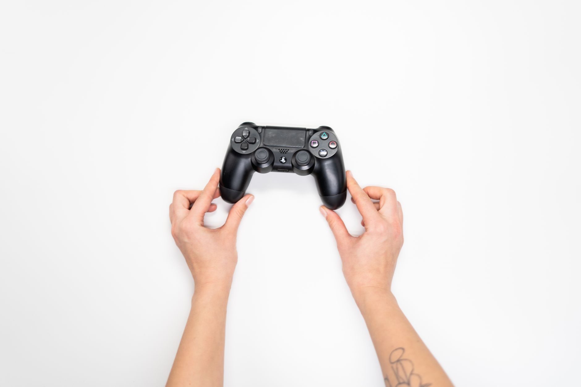 Person holding a gaming controller with thumbs on analog sticks during gameplay