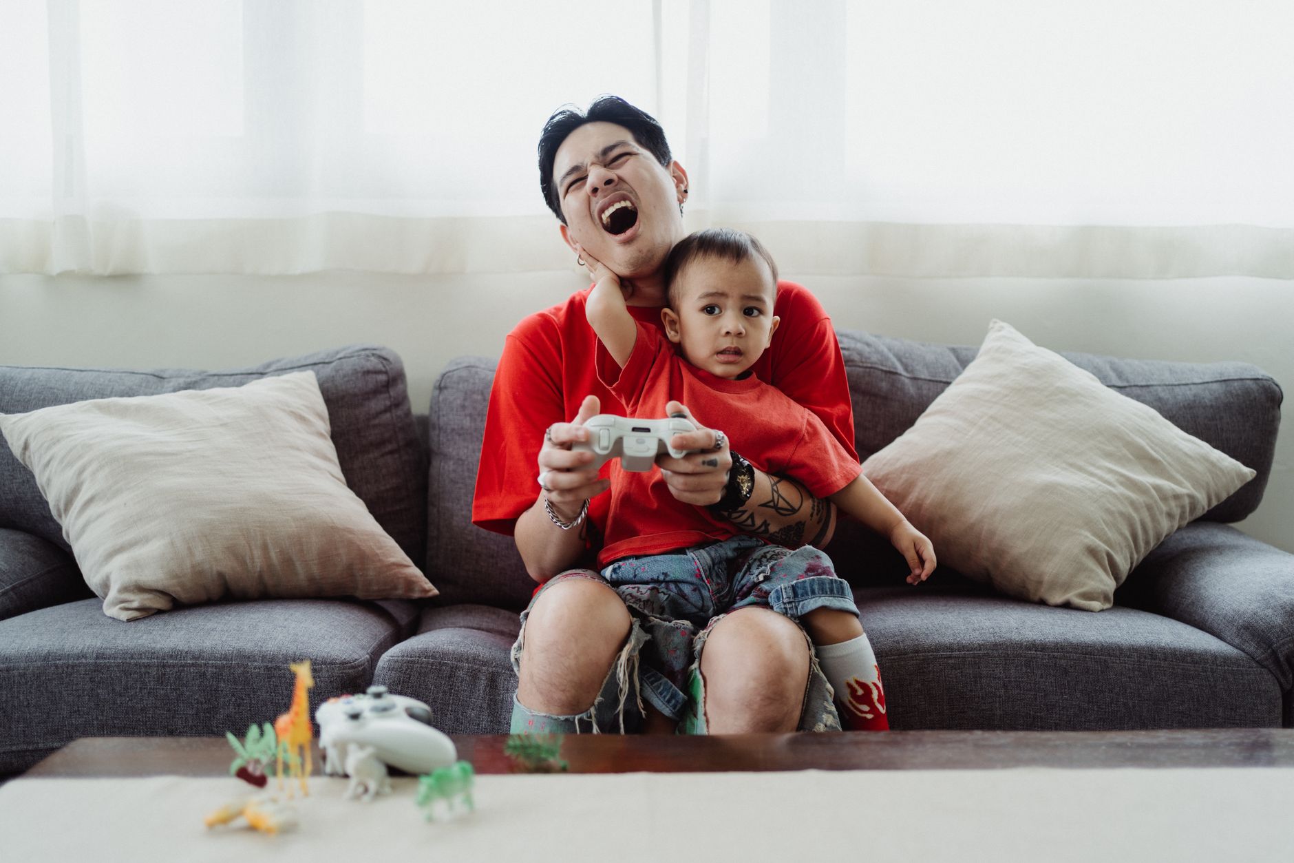 A parent and young child sitting together playing a video game on a TV screen