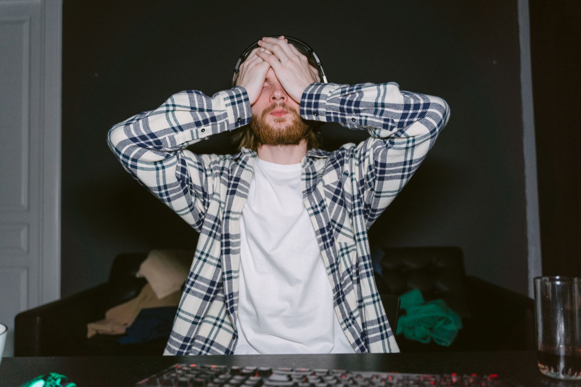 Person sitting at a gaming setup looking frustrated at a screen