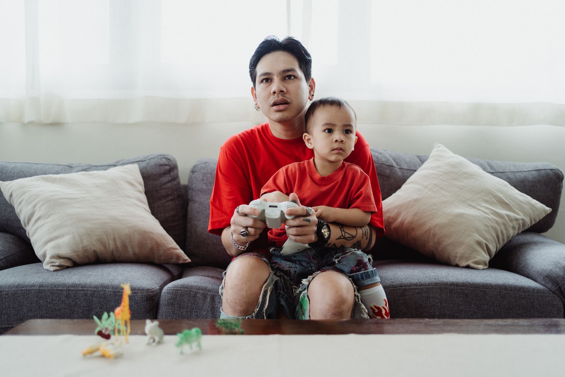 Parent and child sitting together with a game controller, child looking disengaged