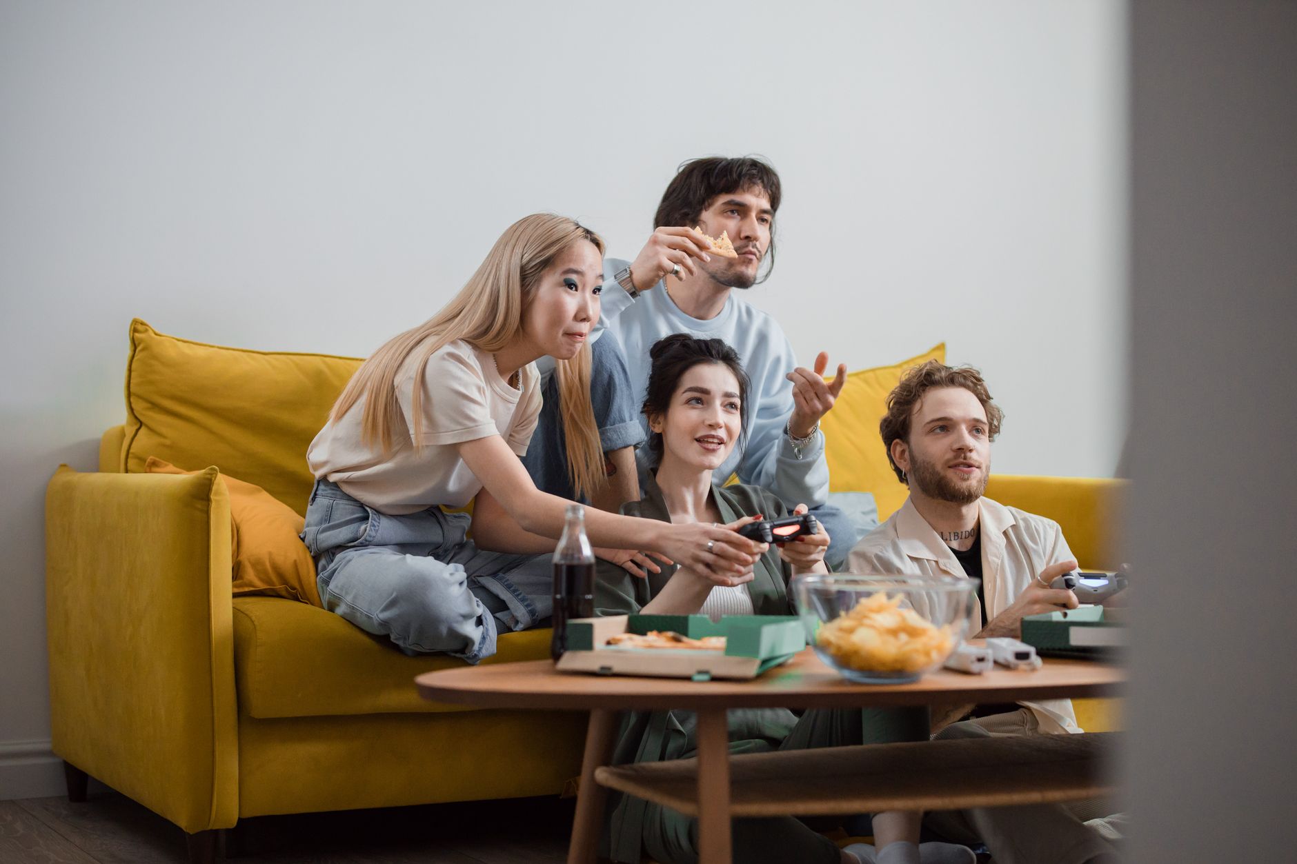 A gamer sitting in a living room playing a game on a large television screen