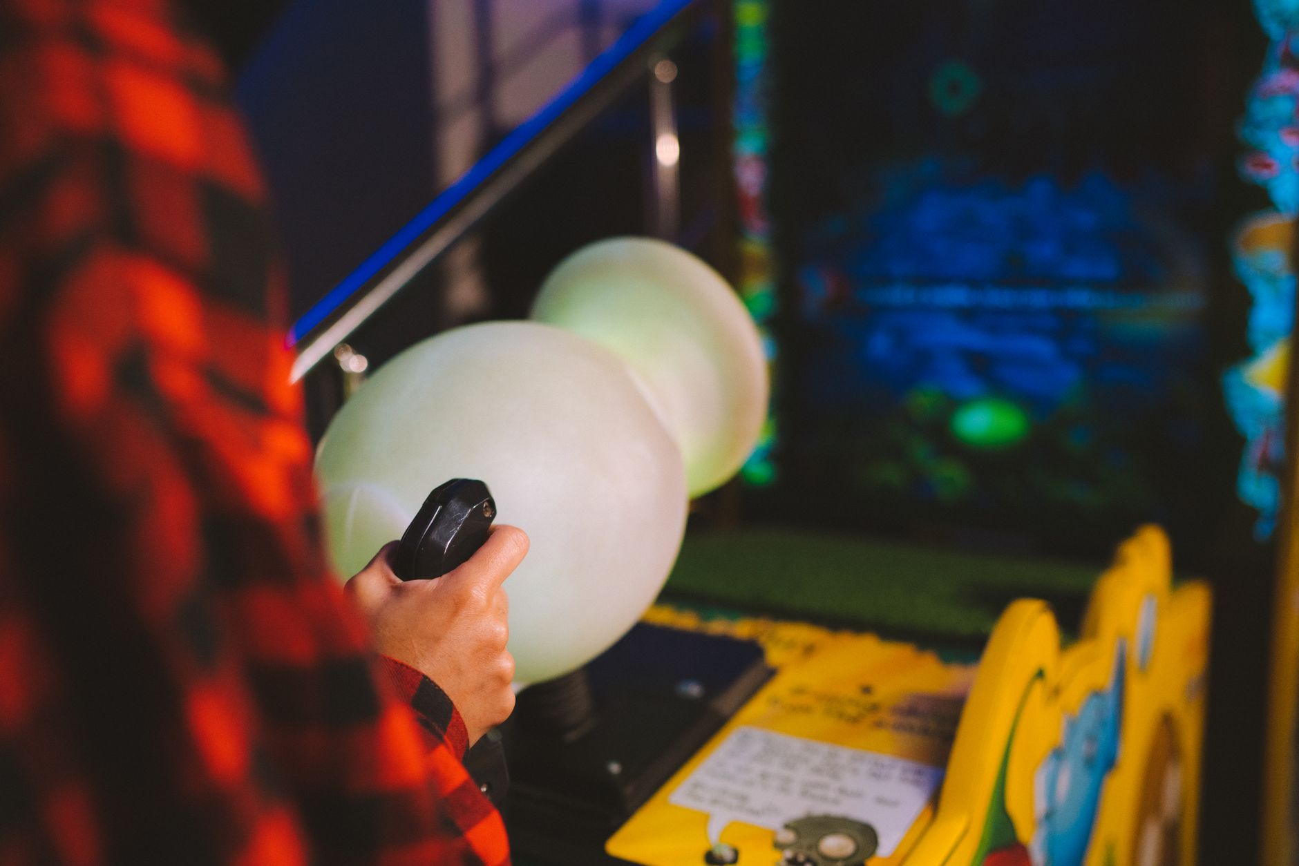 A glowing arcade game screen displaying colorful pixel graphics in a dark room